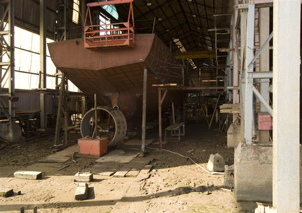 Photo:View of someone working on a ship inside the boat building shed